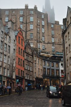 a city street filled with lots of tall buildings and people walking on the side walk