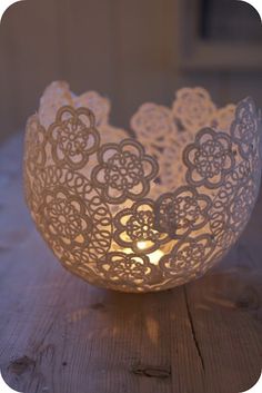 a white lace doily bowl sitting on top of a wooden table