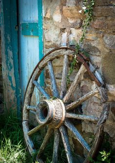 an old wooden wheel leaning against a stone wall