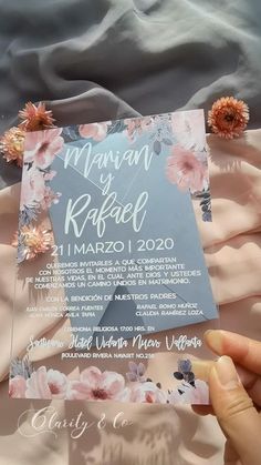 a person holding up a wedding card with flowers on the front and back, which reads manu de radal