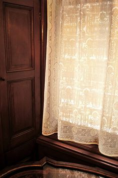 the curtains are hanging on the window sill in front of the wooden cupboards