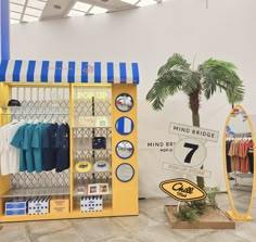 a store display with clothing and other items on it's shelves in front of a palm tree