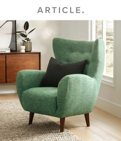 a green chair sitting on top of a wooden floor next to a white and black rug