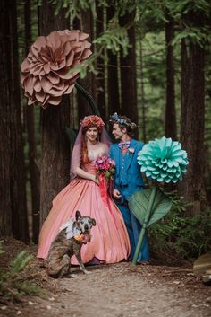 a man and woman dressed up in costume standing next to each other with a dog