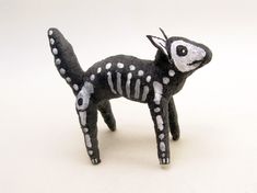 a black and white skeleton cat figurine on a white surface with one eye open