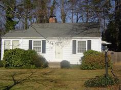 a small white house sitting in the middle of a yard