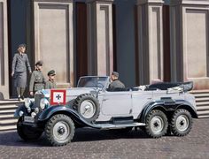 an old model car is parked in front of some people and another man standing next to it