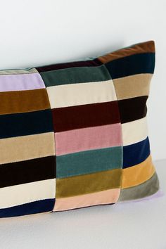 a multicolored striped pillow sitting on top of a white table next to a wall