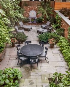 an outdoor patio with tables and chairs surrounded by plants