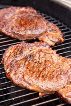 two steaks are cooking on the grill