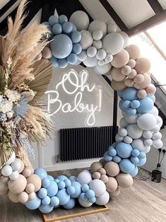 a balloon arch is decorated with blue, white and beige balloons that spell out oh baby