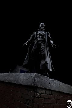 the dark knight statue stands on top of a brick wall in front of a black background