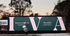 a person walking past a large sign on the side of a road with trees in the background