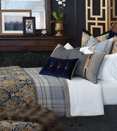 a bed with many pillows on top of it and a framed picture above the headboard