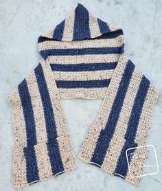 a blue and white striped knitted sweater with hood on concrete surface, top view