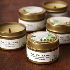 four candles sitting on top of a wooden table next to each other with the words pacific trail printed on them