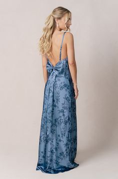 the back of a woman wearing a long blue dress with a floral print on it