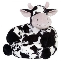 a black and white cow sitting down with its legs crossed