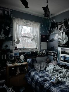 an unmade bed sitting next to a window in a room with pictures on the wall