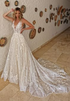 a woman standing in front of a wall wearing a wedding dress with an open back