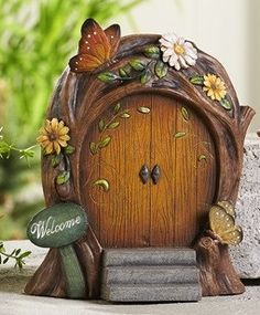 a small wooden door with flowers and butterflies on the front, sitting next to a potted plant