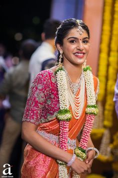 a woman in an orange and pink sari smiles at the camera while standing next to other people