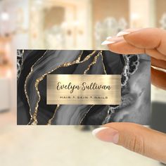 a person holding up a business card with a gold foil design on the front and back