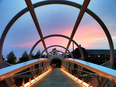 the walkway is lit up at night and there are lights on both sides of it