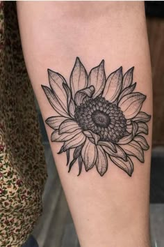 a black and white sunflower tattoo on the leg