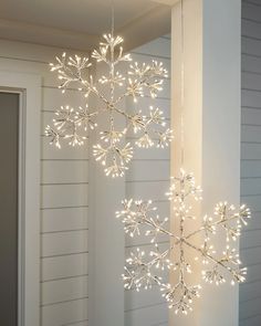 a lighted snowflake hanging from the side of a house in front of a door