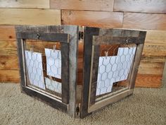 two wooden frames with chicken wire in them on carpeted floor next to wood wall