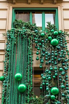 green christmas decorations hanging from the side of a building