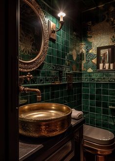 a green tiled bathroom with gold sink and round mirror above the toilet area, along with a black countertop