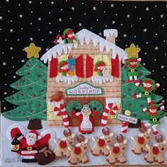 a christmas scene with santas and elves in front of a gingerbread house made out of felt