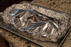 an aluminum foil covered tray on top of a granite countertop next to a stove