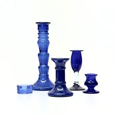 a group of blue glass vases sitting on top of a white table next to each other