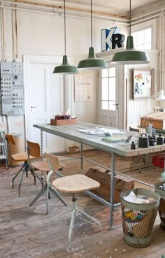 an industrial style kitchen with wooden floors and green pendant lights hanging from the ceiling over the island