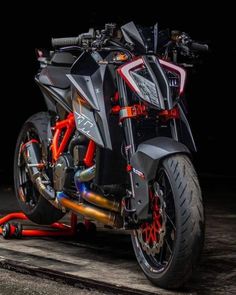 a black and red motorcycle is parked on the street in front of a dark background