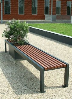 a wooden bench sitting in front of a brick building with a potted plant on it