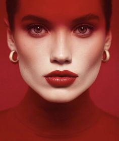 a woman with red makeup and large hoop earrings on her head, in front of a red background