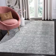 a living room with a pink chair and rug