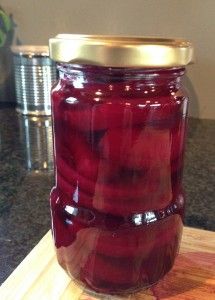 a jar filled with pickles sitting on top of a wooden cutting board