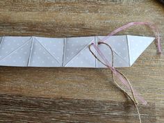 an origami piece is sitting on top of a wooden table next to scissors and thread