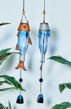 two blue glass fish hanging from hooks on a wall