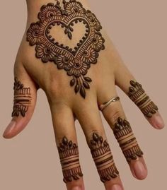 a hand with henna tattoos on it and an intricate heart shaped design in the middle