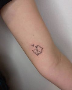 a small book tattoo on the left inner arm, with stars coming out of it