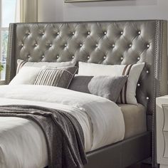 a bed with white linens and silver headboard next to a window in a bedroom