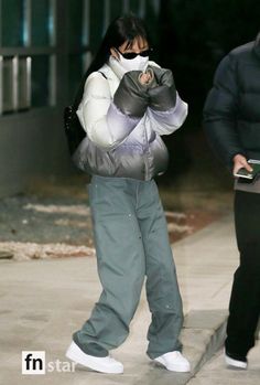 a woman is walking down the street while talking on her cell phone and wearing a mask