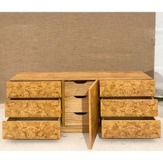 a wooden cabinet with four drawers sitting on top of a cement floor next to a wall