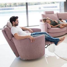 a man and woman are sitting on pink chairs in the living room with their children